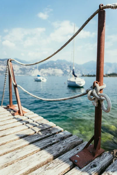 Sailing: Wooden dock pier, sailing boats in the background. — Stock Photo, Image