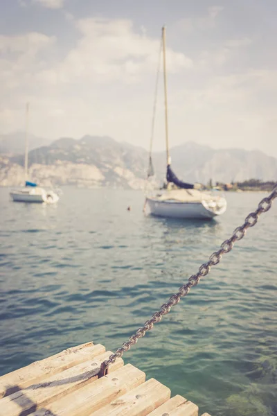 Sailing: Wooden dock pier, sailing boats in the background. — Stock Photo, Image