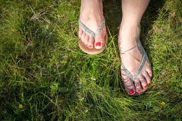 Letní čas: překlápět pláty nebo sandály v zelené trávě — Stock fotografie