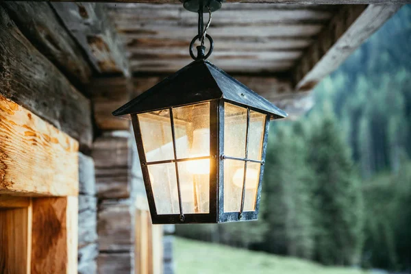Linterna está colgando en la terraza de una antigua cabaña de madera — Foto de Stock