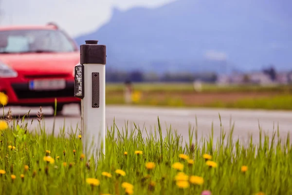 夏の道路:リフレクターポスト、車、花、緑の草 — ストック写真