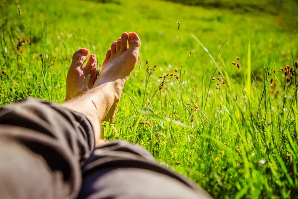 Escalofriante en la hierba verde: Piernas de un joven, relajante, summ —  Fotos de Stock