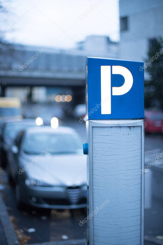 Parking in midtown: parking machine, evening scenery and cars