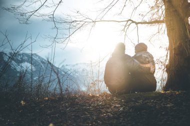 Pastoral dağ güneşin batışını sahne: genç oturma çift