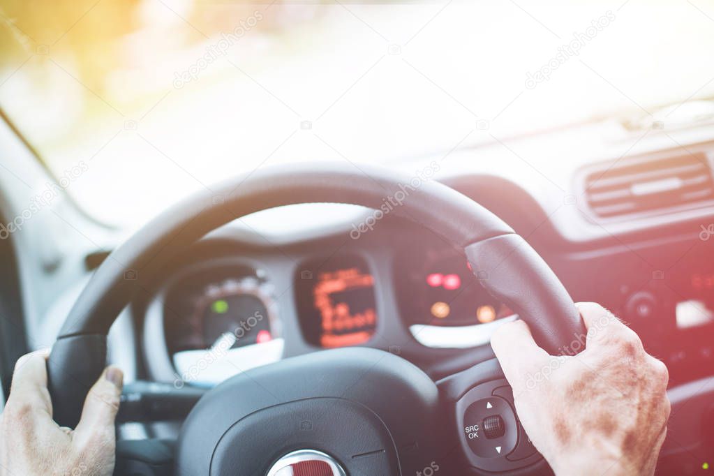 Modern car interior: Male hands on a sports car steering wheel