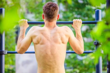Yaz aylarında egzersiz: Genç fit Kafkas adam pull up yapıyor. Na