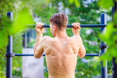 Yaz aylarında egzersiz: Genç fit Kafkas adam pull up yapıyor. Na