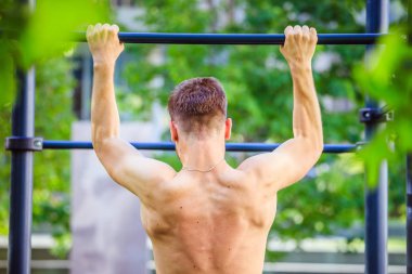 Yaz aylarında egzersiz: Genç fit Kafkas adam pull up yapıyor. Na