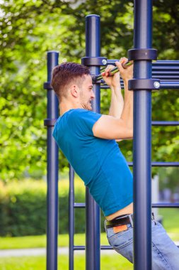 Yaz aylarında egzersiz: Genç fit Kafkas adam pull up yapıyor 