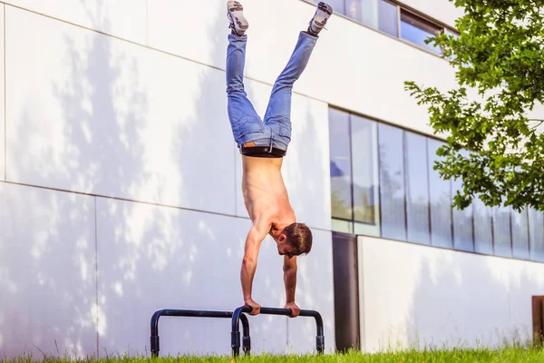 Entrenamiento en verano: Hombre caucásico en forma joven está haciendo un soporte de mano —  Fotos de Stock