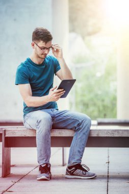 Kampüste tablet bilgisayar kullanan öğrenci. Açık havada, kentsel duygu