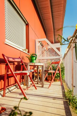 Rahat yaz balkon: Kırmızı sandalye, güneş, kimse