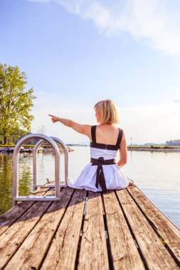Beyaz elbise ile güzel genç kadın bir footbridg üzerinde oturuyor