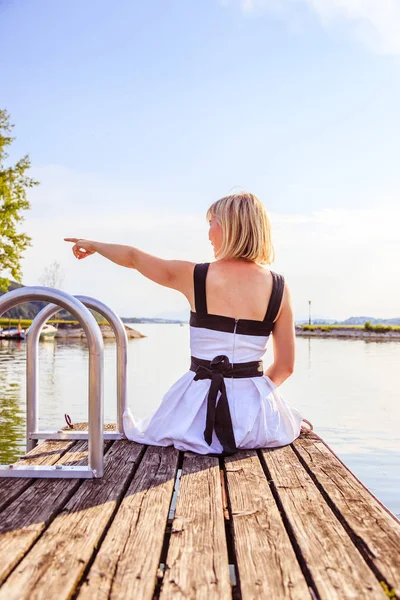 Beyaz elbise ile güzel genç kadın bir footbridg üzerinde oturuyor