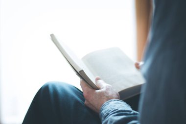 Kıdemli adam evde bir kitap okuyor, seçici odak