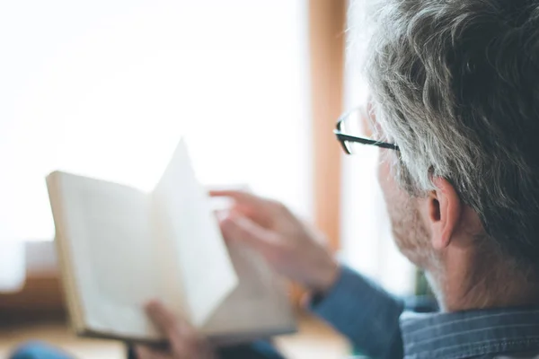 Sênior está lendo um livro em casa, foco seletivo — Fotografia de Stock