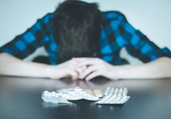 Hombre deprimido tomando drogas. Joven sentado en una mesa, drogas — Foto de Stock