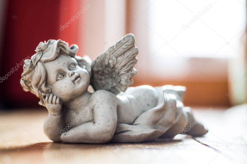 Sculpture of a white guardian angel lying on the wooden floor