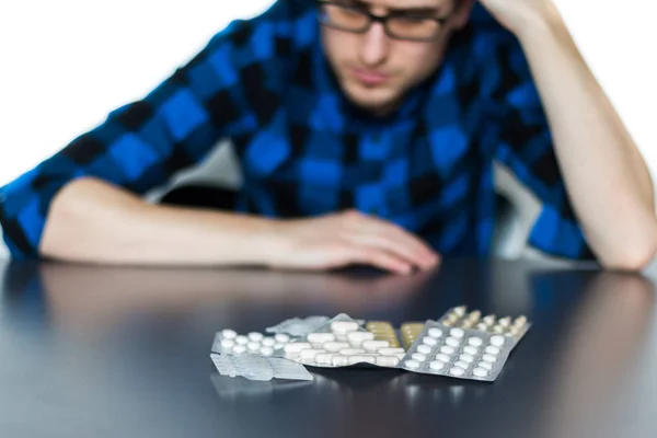 Depressed man taking drugs. Young man sitting on a table, drugs — Stock Photo, Image