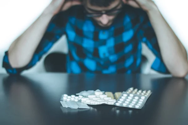 Homem deprimido a tomar drogas. Jovem sentado em uma mesa, drogas — Fotografia de Stock