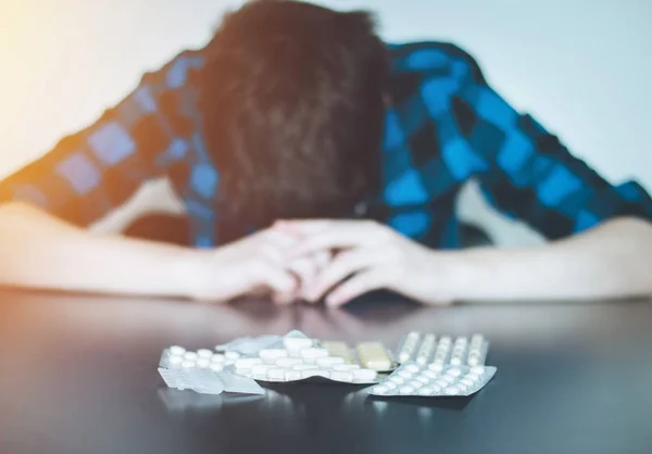 Hombre deprimido tomando drogas. Joven sentado en una mesa, drogas —  Fotos de Stock