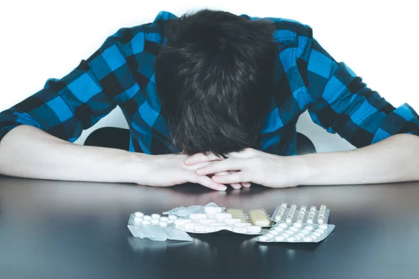 Hombre deprimido tomando drogas. Joven sentado en una mesa, drogas —  Fotos de Stock