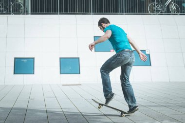 Erkek kaykaycı atlama numarası yapıyor.