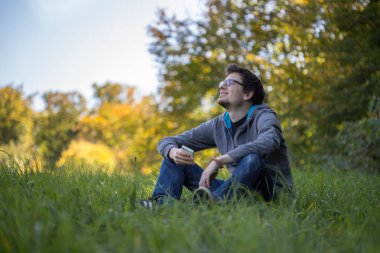 Dışarıdaki yeşil çimlerde telefonla rahatlayan bir adam.