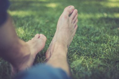 Erkek bacakları yeşil çimlerde yatıyor.