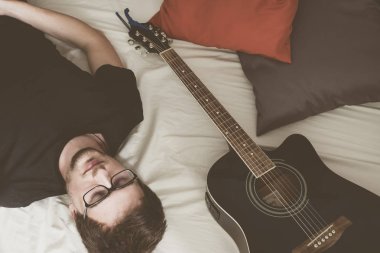 Gitarlı bir adam odada uyuyor.