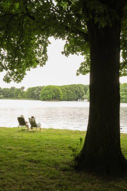 Nehirdeki sandalyede oturan çift.
