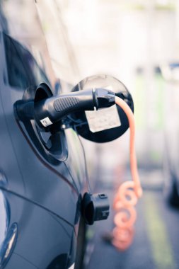 Elektrikli araba şarjı için güç kaynağı. Elektrikli araba şarj istasyonu. Şarj edilen bir elektrikli arabaya takılan güç kaynağını kapatın.