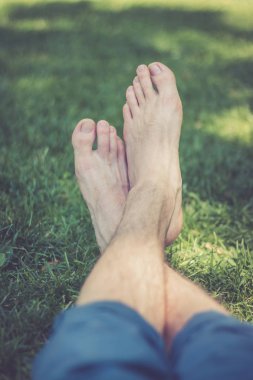 Erkek bacakları yeşil çimlerde yatıyor.