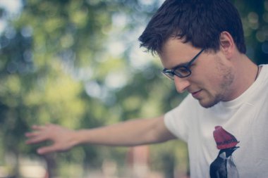 Parkta sakallı, gözlüklü genç adam.