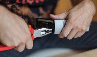 Adamın eli güçlü bir şekilde metal bir pense tutuyor.