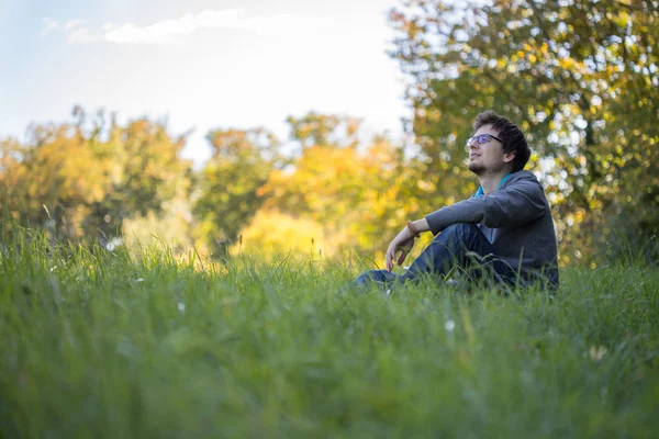 Yeşil çimlerde dinlenen bir adam.