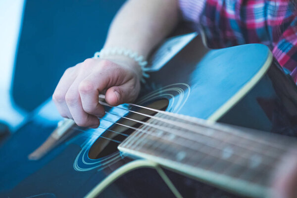 Young man playing a sunburst western guitar