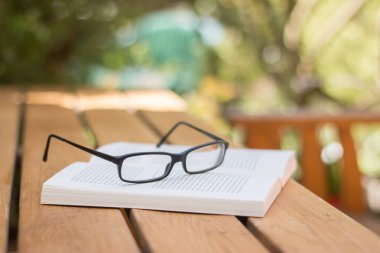 Kitap ve bardaklar parktaki masanın üstünde.