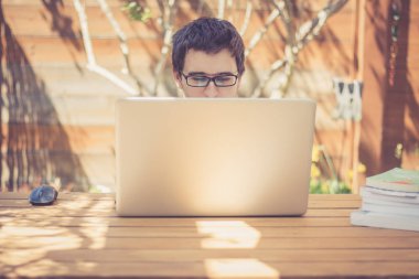 Genç adam dizüstü bilgisayar kullanıyor.