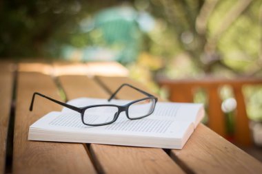 Kitap ve bardaklar parktaki masanın üstünde.