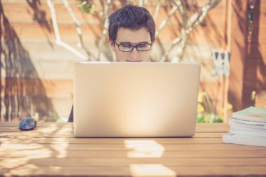 Genç adam dizüstü bilgisayar kullanıyor.