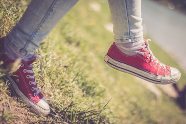 Parkta kırmızı spor ayakkabılı kadın bacakları.