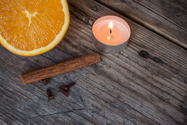 orange,cinnamon stick and candle on background,close up