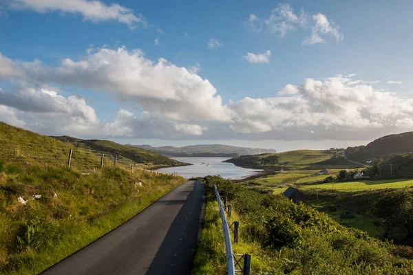 asphalt road with blue sky and green grass