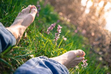 Erkek bacakları yeşil çimlerde yatıyor.