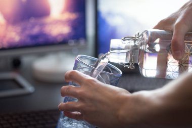 Kırpılmış insan görüntüsü bardağa su döküyor. 