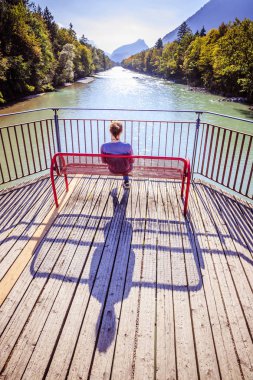 Güzel genç bir kadın bankta oturuyor. 