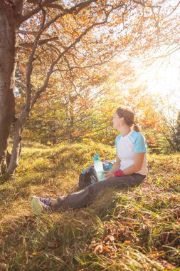 Sırt çantalı dağcı ormanda oturuyor.
