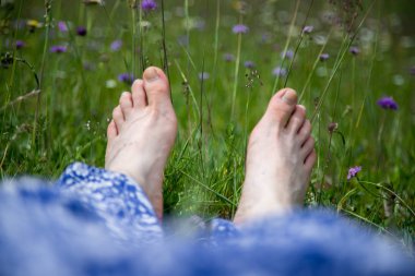 Kadın bacakları yeşil çimlerde yatıyor.