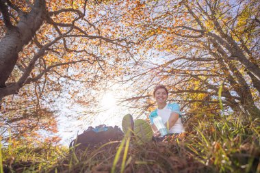 Sırt çantalı dağcı ormanda oturuyor.